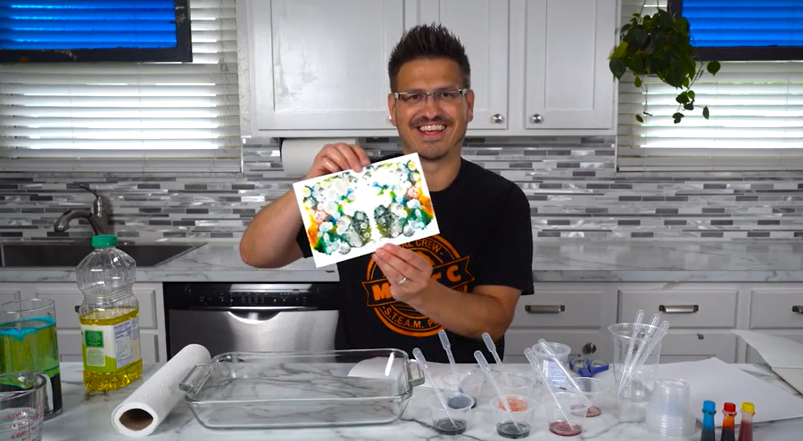 Mr. C holding an abstract artwork made by spreading food dye across shaving cream