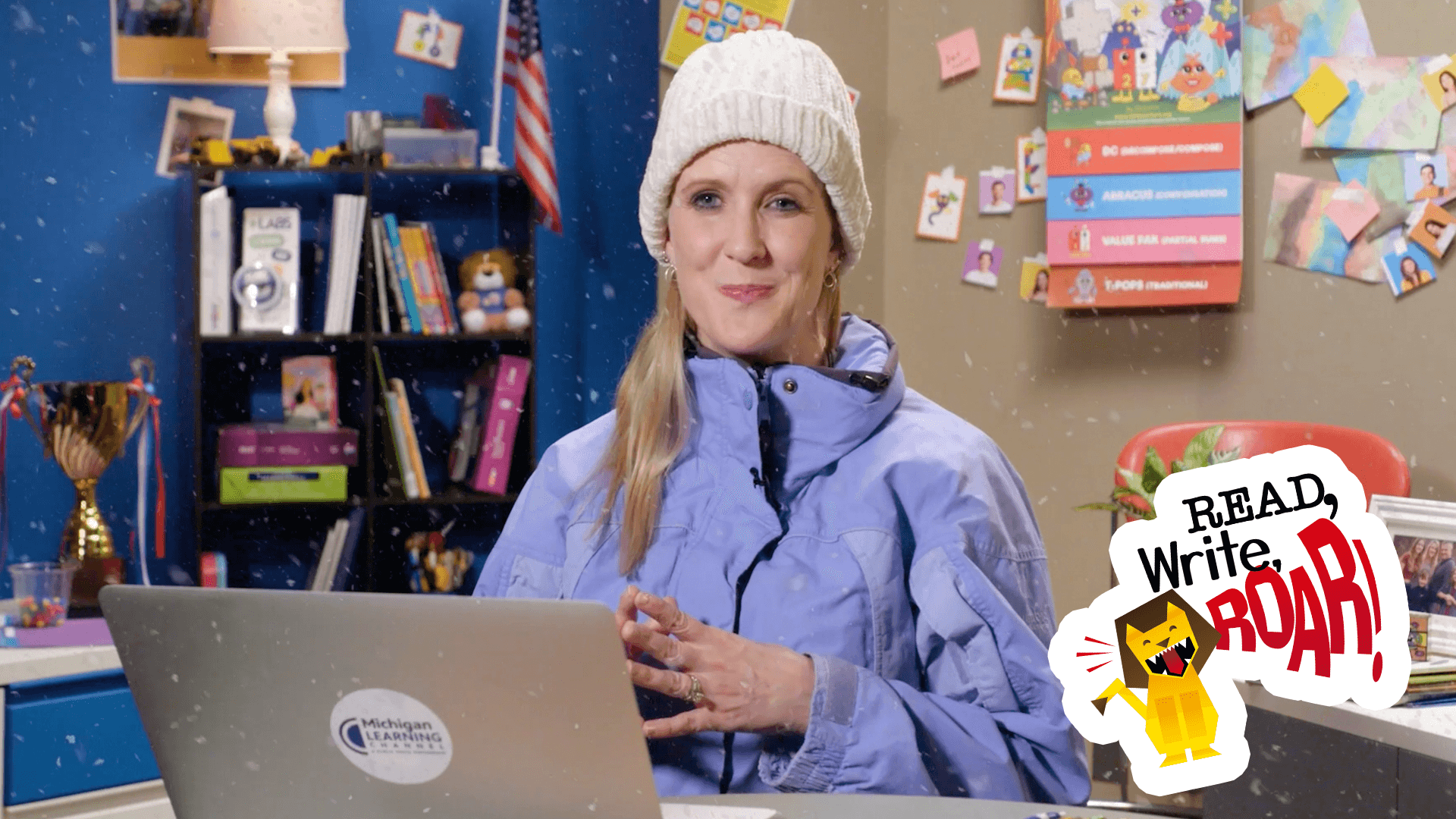 Woman in jacket and winter hat sitting t a desk in a classroom